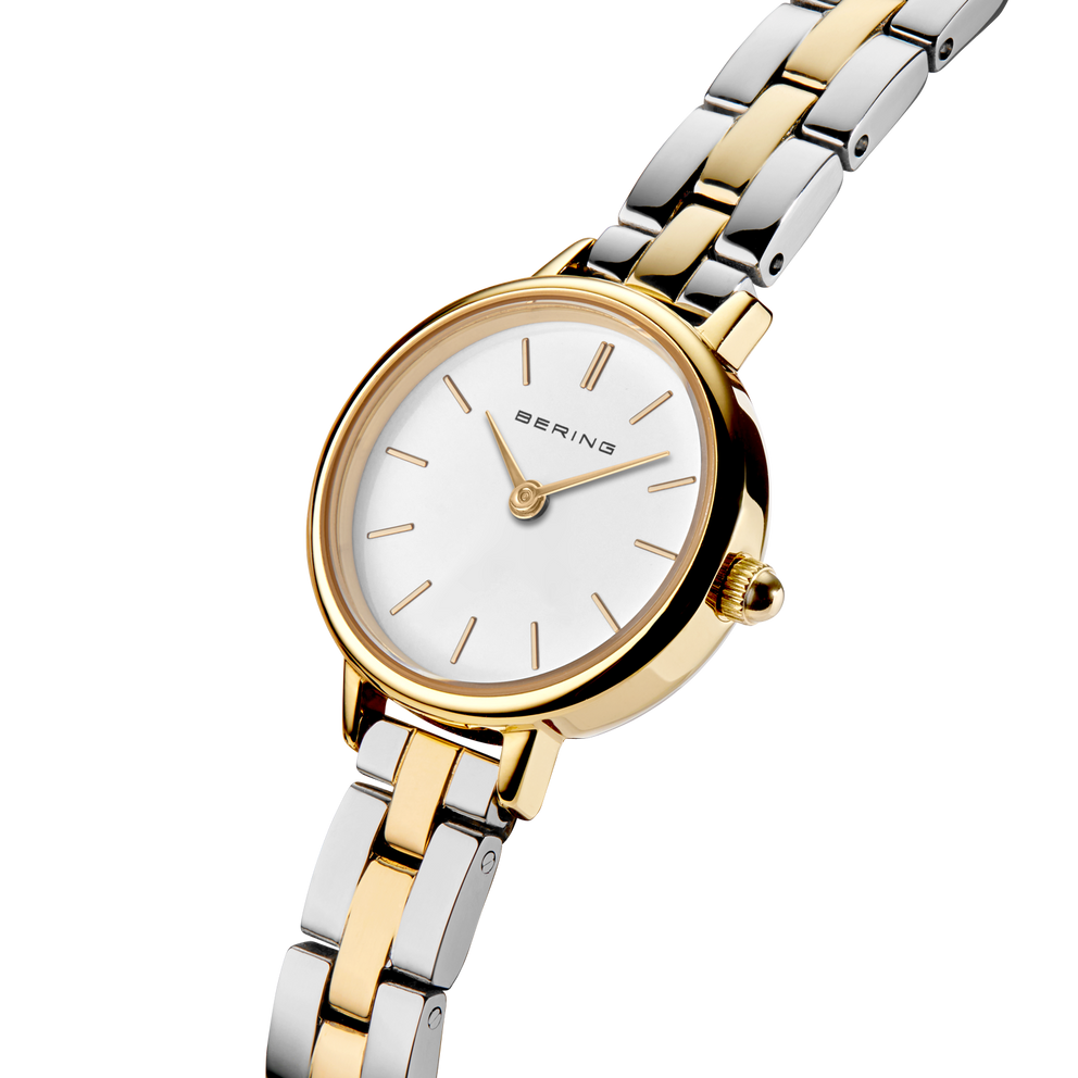 Angled close-up of the white dial and gold-tone case beside the silver- and gold-tone link bracelet.