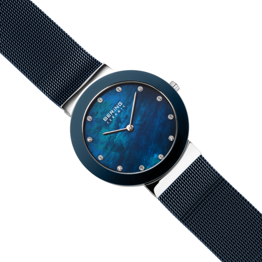 Diagonal overhead view of the mottled blue dial, silver-tone with blue bezel case and blue mesh strap.