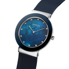 Angled close-up of the mottled blue dial and silver-tone with blue bezel case beside the blue mesh strap.