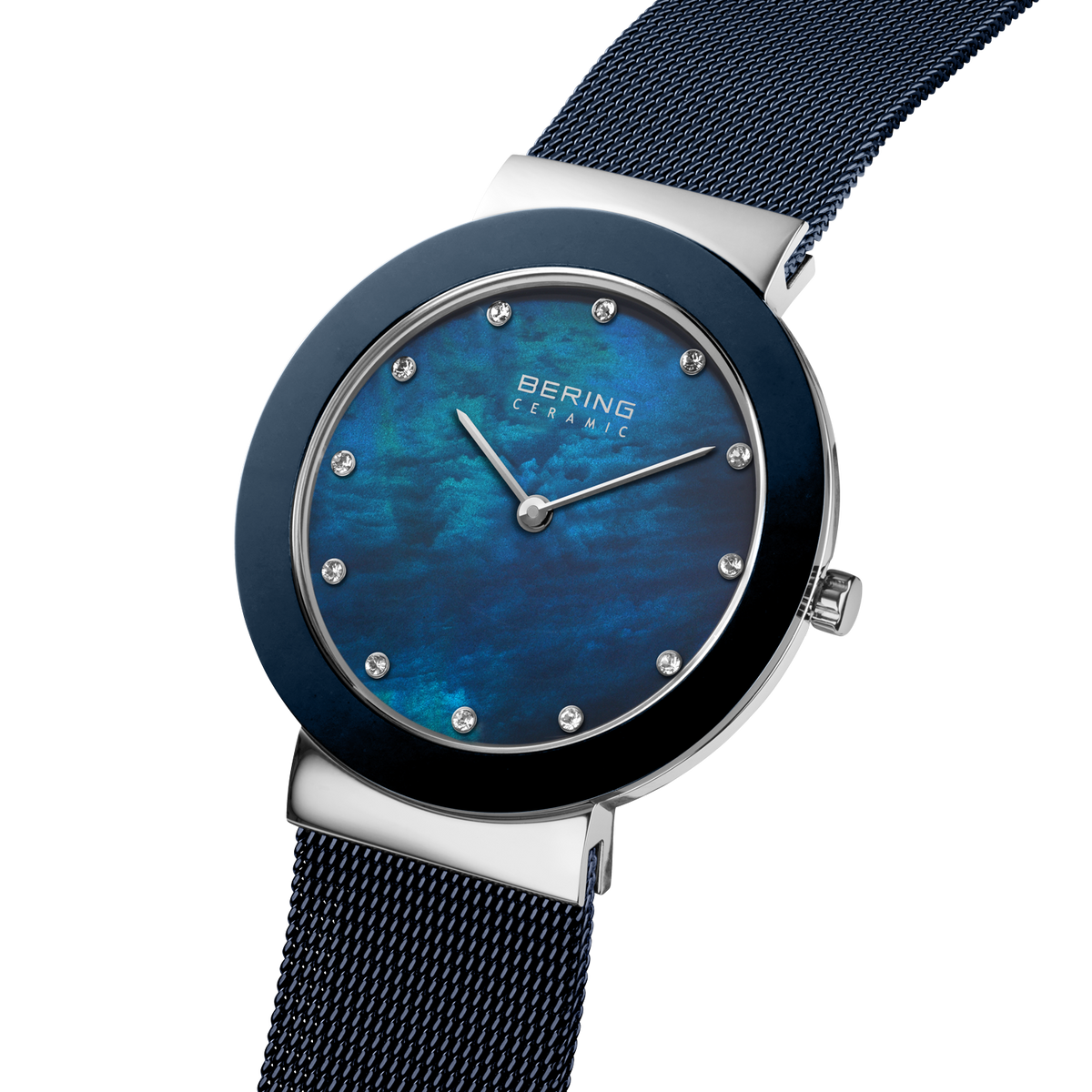 Angled close-up of the mottled blue dial and silver-tone with blue bezel case beside the blue mesh strap.