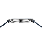 Side profile of the silver-tone with blue bezel watch case and crown between the ends of the blue mesh strap.