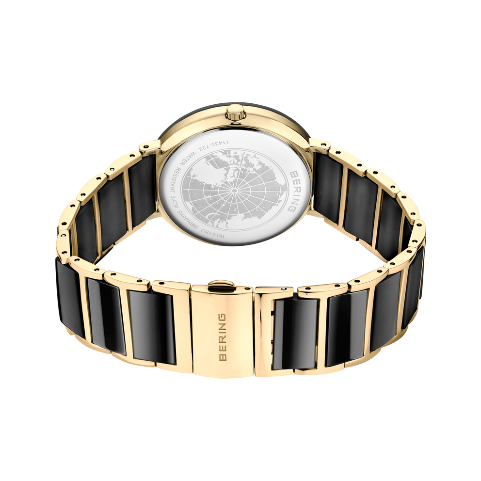 Vista posterior del reloj, con pulsera dorada de eslabones con centros negros formando un aro y cierre cerrado.