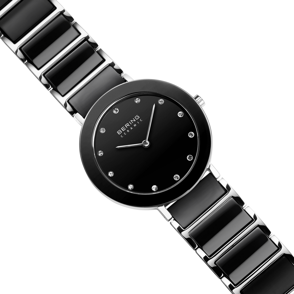Diagonal overhead view of the black dial with bright dot markers, silver-tone with black bezel case and black-centered silver-tone link bracelet.