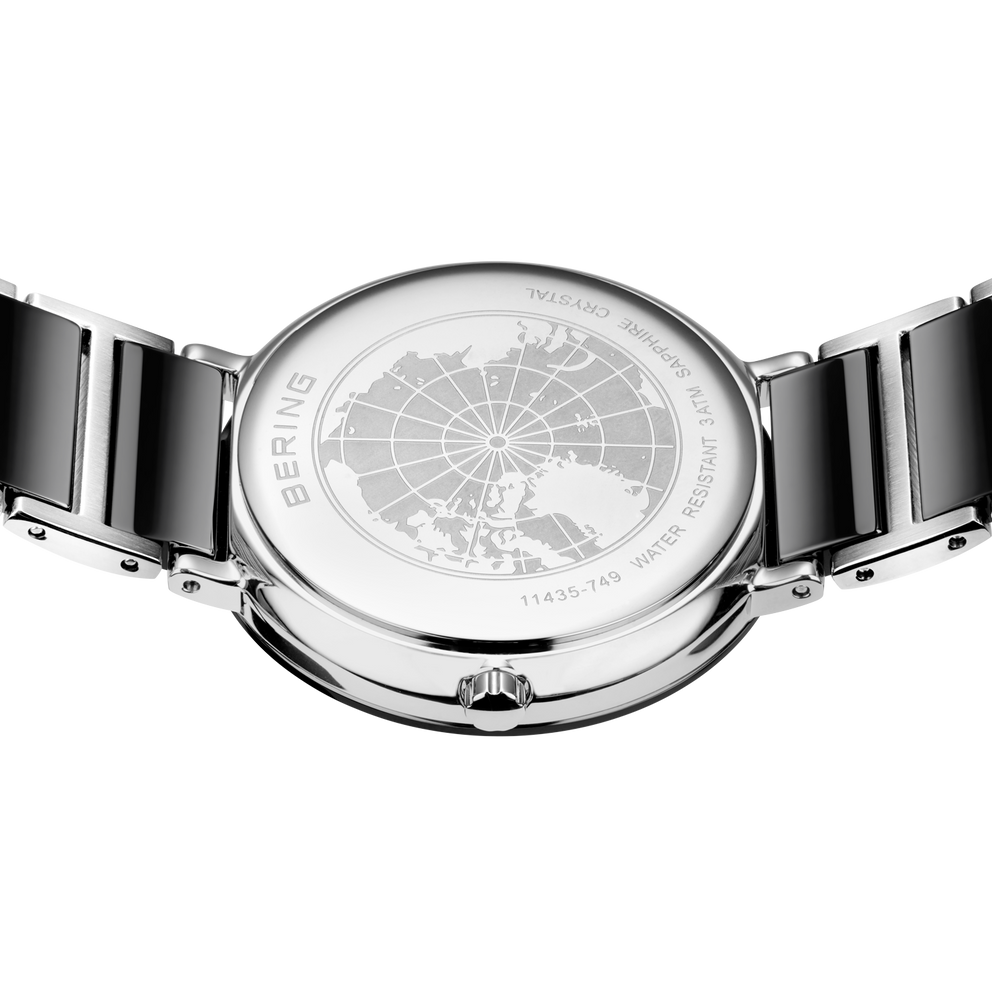 Engraved watch case back with the black-centered silver-tone link bracelet extended to either side.
