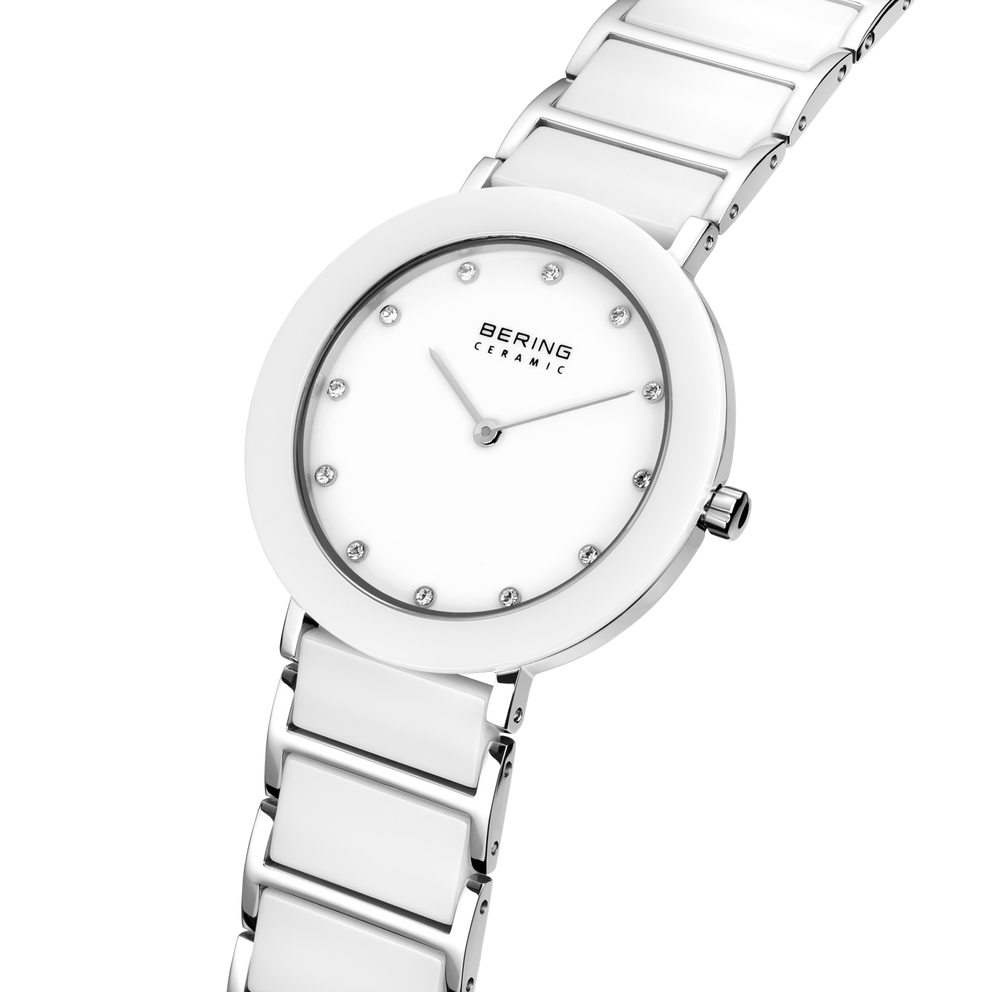 Angled close-up of the white dial with bright dot markers and silver-tone with white bezel case beside the white-centered silver-tone link bracelet.