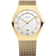 Front view: white dial with gold-tone numerals, gold-tone case and gold-tone mesh strap.