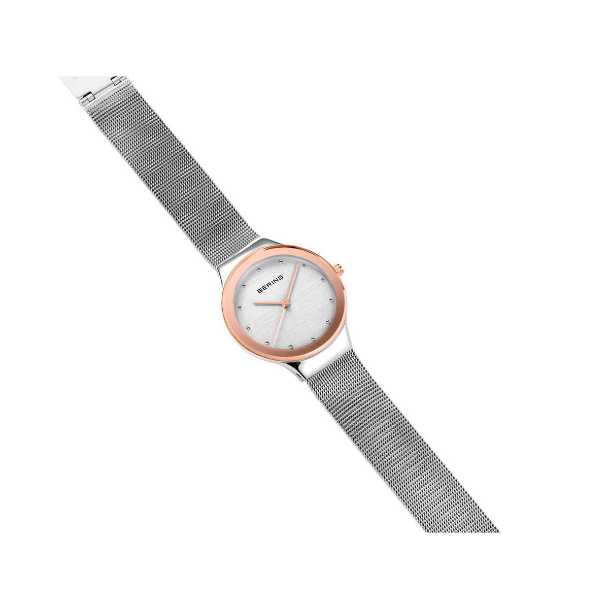 Diagonal overhead view of the pale dial with bright dot markers, oval rose-tone case and silver-tone mesh strap.