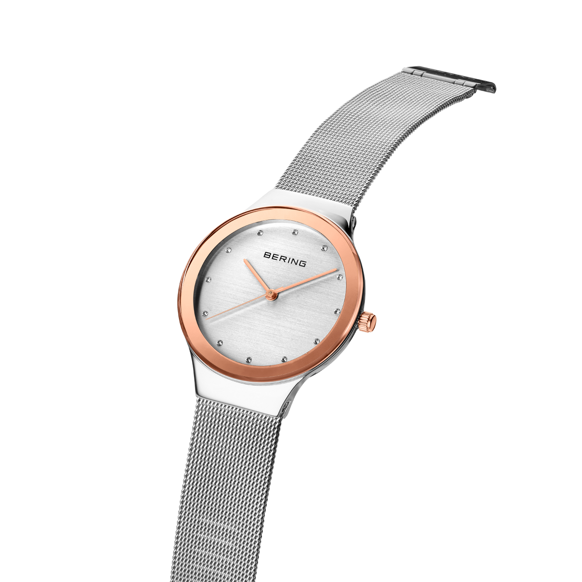 Angled close-up of the pale dial with bright dot markers and oval rose-tone case beside the silver-tone mesh strap.