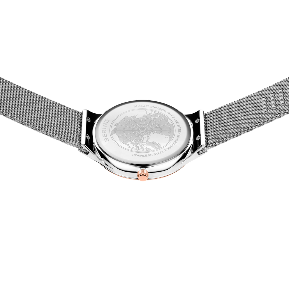 Engraved watch case back with the silver-tone mesh strap extended to either side.