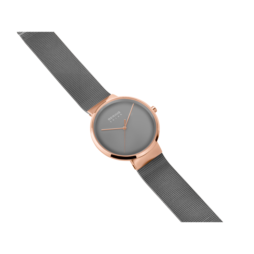 Diagonal overhead view of the grey dial, rose-tone case and grey mesh strap.