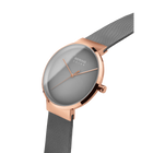Angled close-up of the grey dial and rose-tone case beside the grey mesh strap.