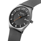 Angled close-up of the dark grey dial with white numerals and dark silver-tone case beside the grey mesh strap.