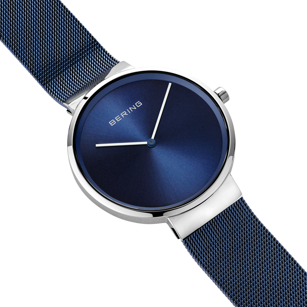 Diagonal overhead view of the blue dial, silver-tone case and blue mesh strap.