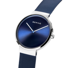 Angled close-up of the blue dial and silver-tone case beside the blue mesh strap.