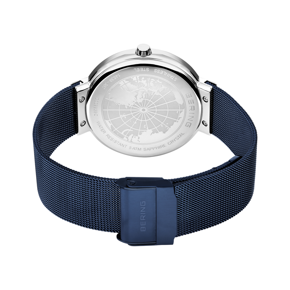 Rear view of the watch with its blue mesh strap looped and fastener closed.