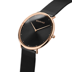 Angled close-up of the black dial and rose-tone case beside the black mesh strap.
