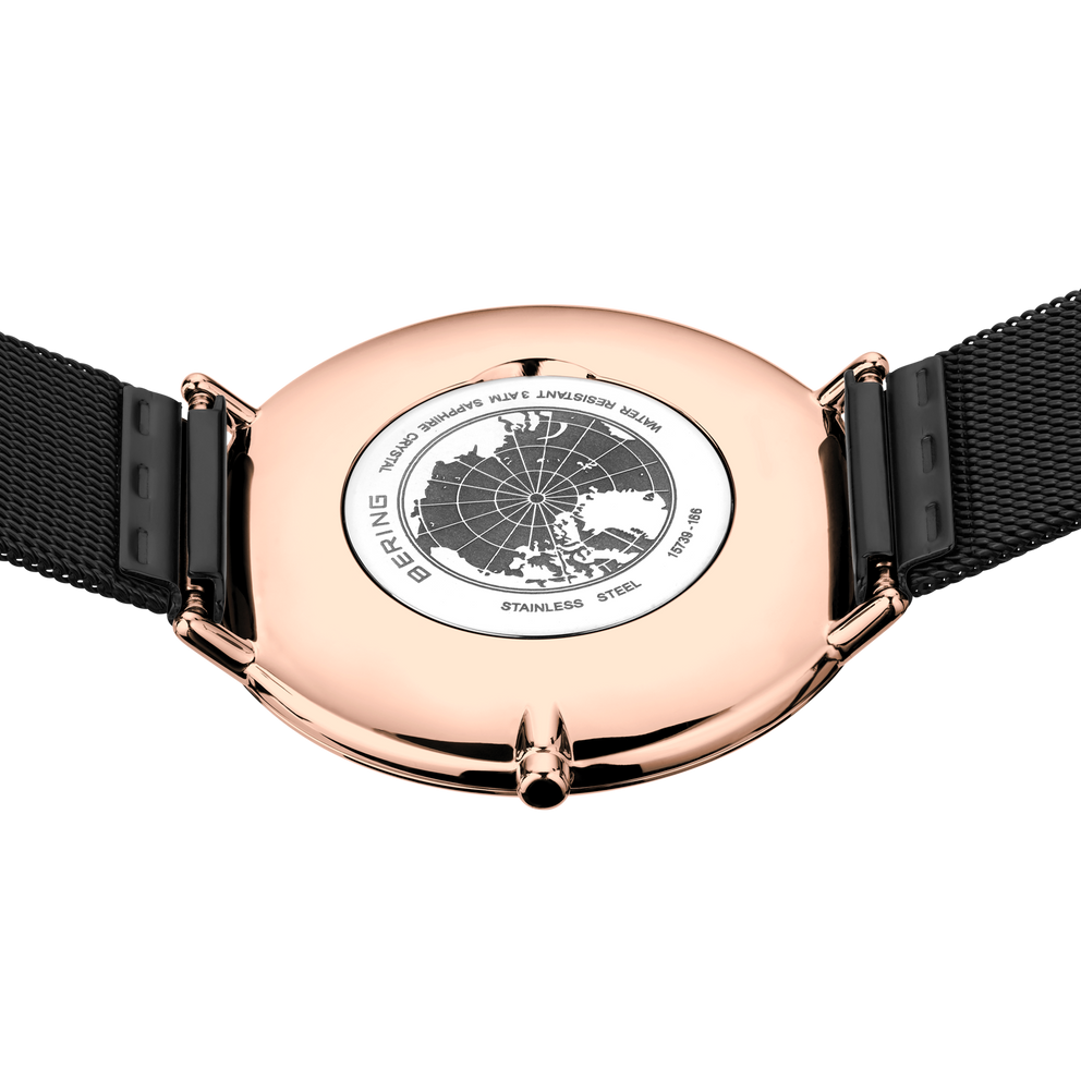 Engraved watch case back with the black mesh strap extended to either side.