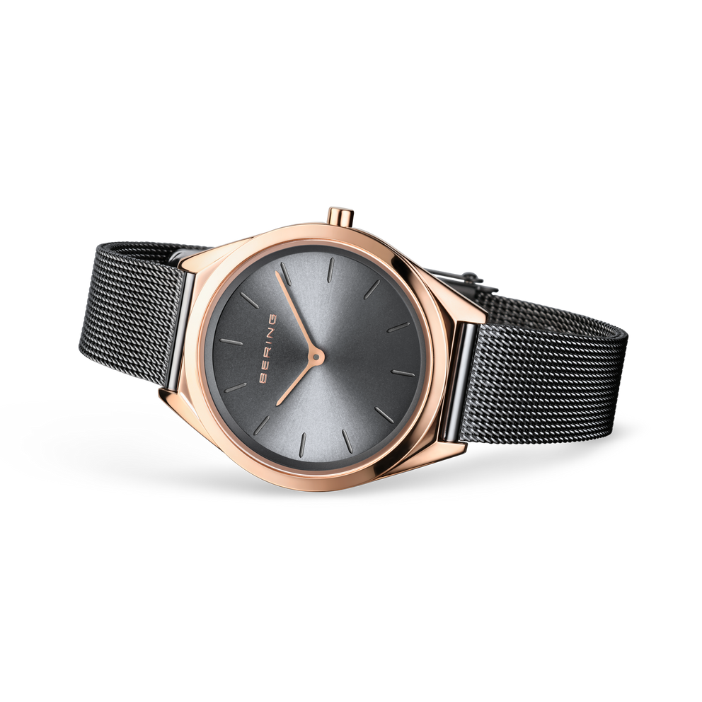 Reloj de esfera gris apoyado en ángulo, con correa de malla gris extendida.