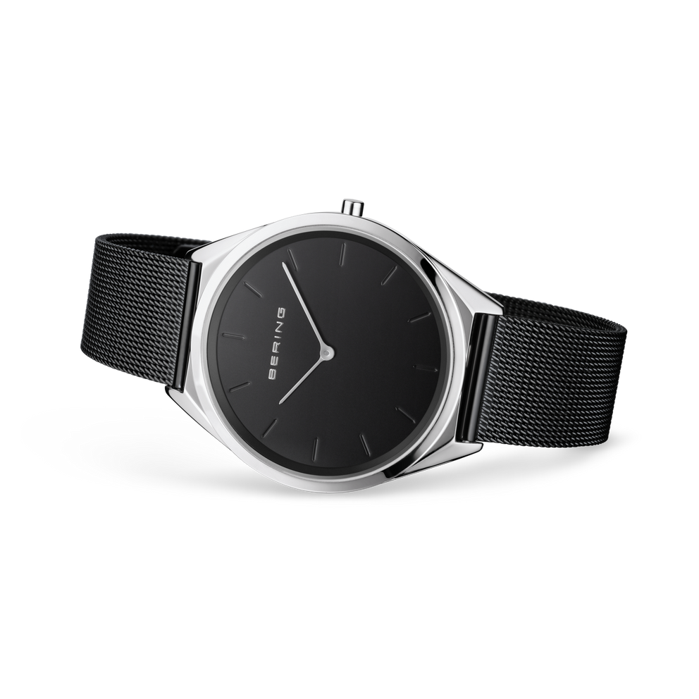 Reloj de esfera negra apoyado en ángulo, con correa de malla negra extendida.