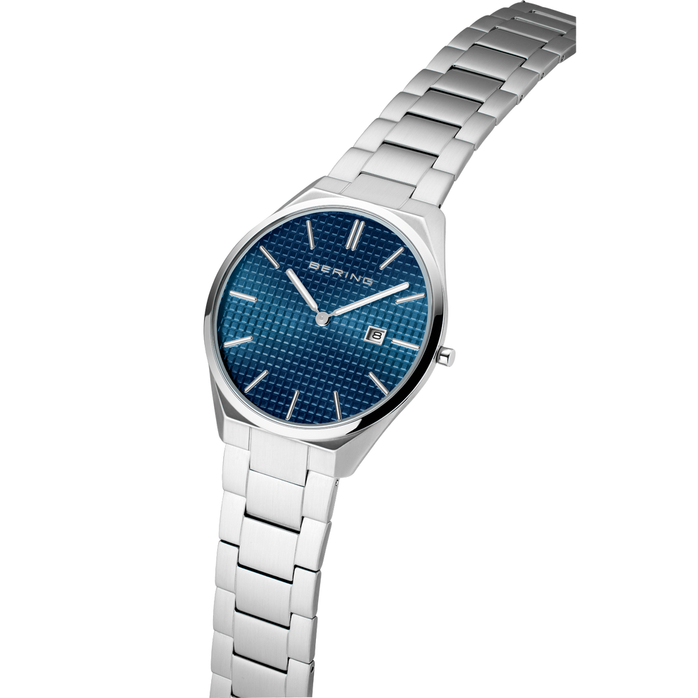 Angled close-up of the textured blue dial and silver-tone case beside the silver-tone link bracelet.