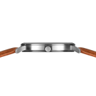 Side profile of the silver-tone watch case and crown between the ends of the stitched brown strap.