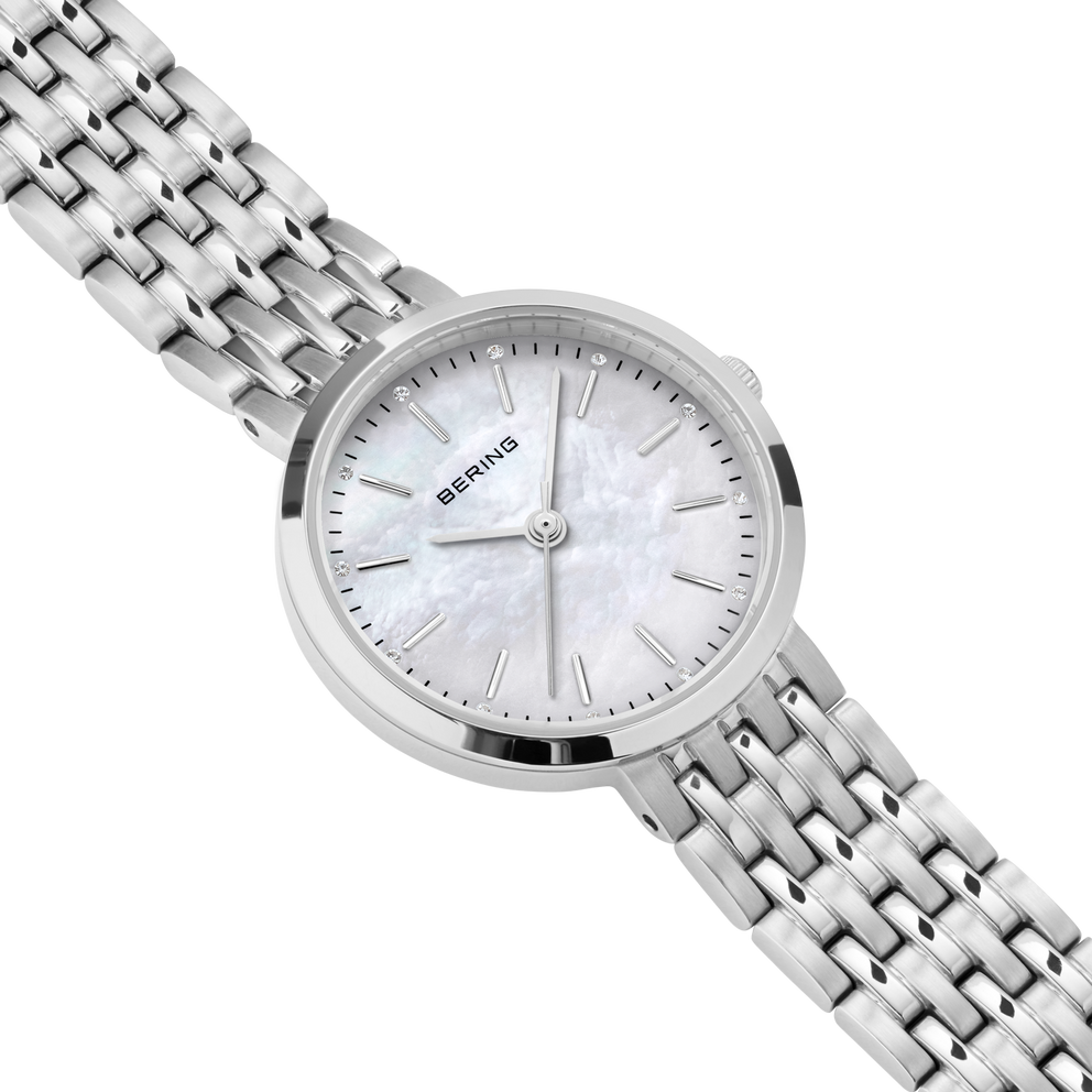 Diagonal overhead view of the pale mottled dial, silver-tone case and silver-tone link bracelet.