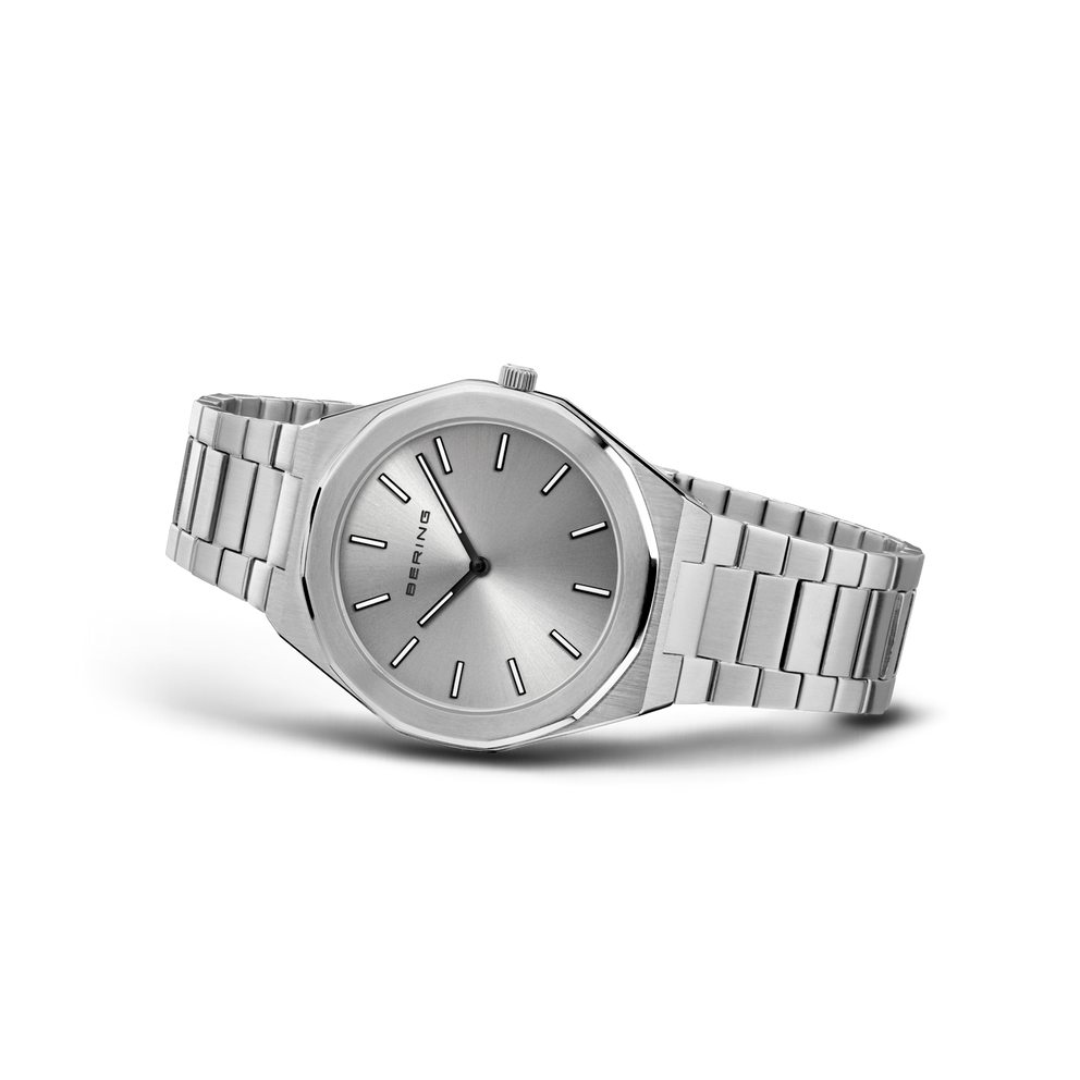 Reloj de esfera gris plateada apoyado en ángulo, con pulsera plateada de eslabones extendida.