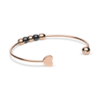 Brazalete abierto rosado girado para mostrar el extremo liso de corazón y un detalle transparente en el otro extremo.