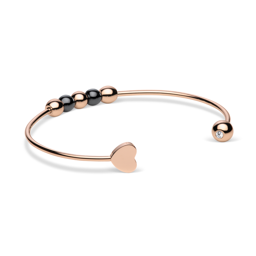 Brazalete abierto rosado girado para mostrar el extremo liso de corazón y un detalle transparente en el otro extremo.