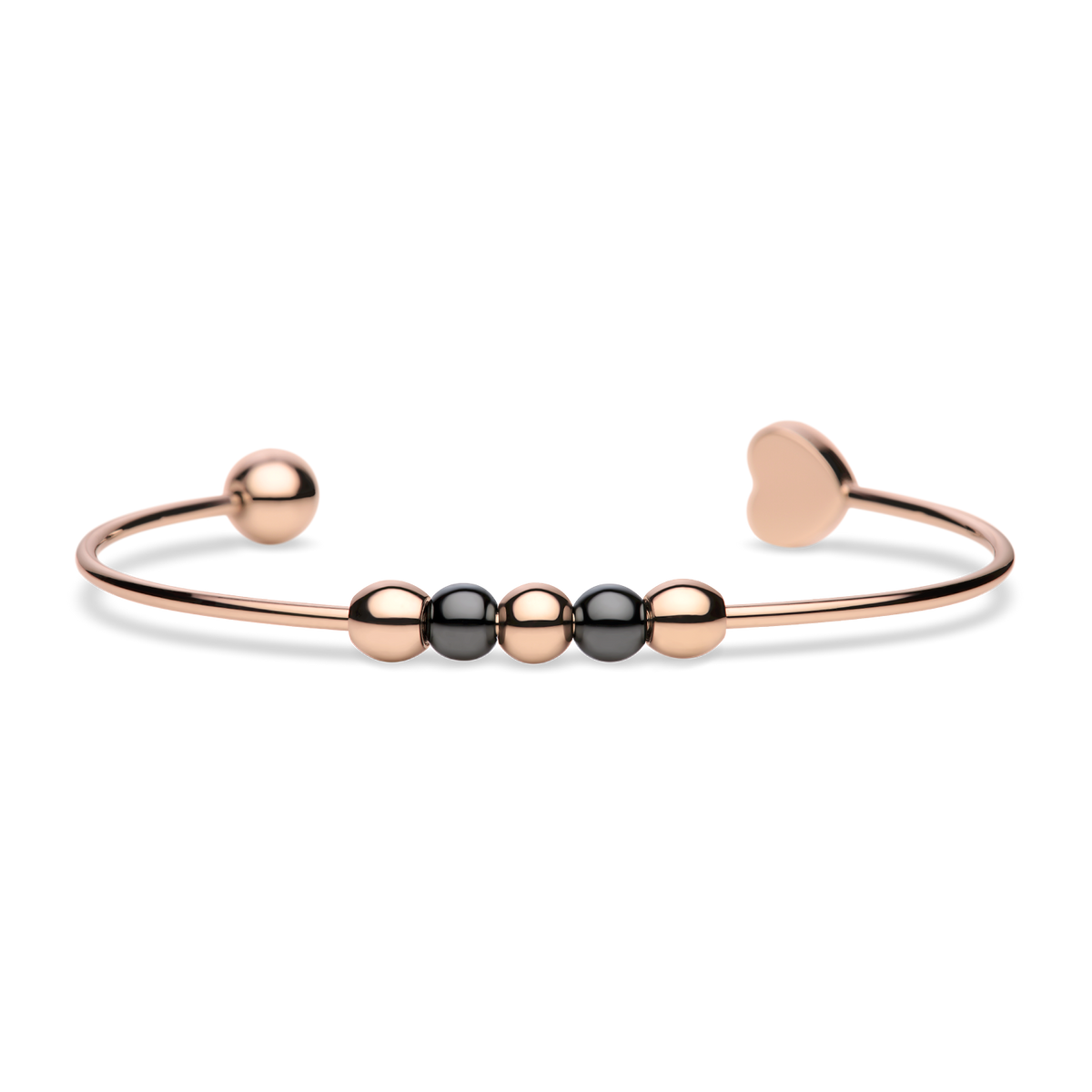 Brazalete abierto rosado con cuentas oscuras y un extremo liso de corazón, tumbado.